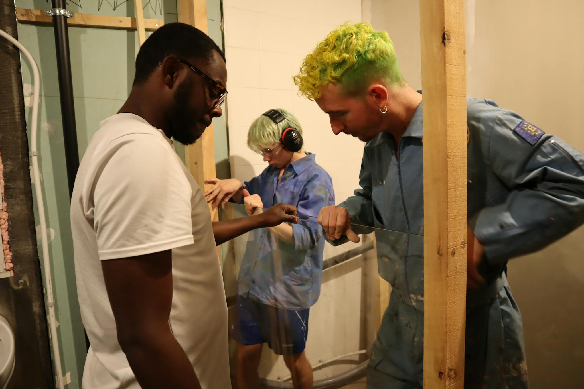 Team of diverse adults working together to install glass in a construction setting.